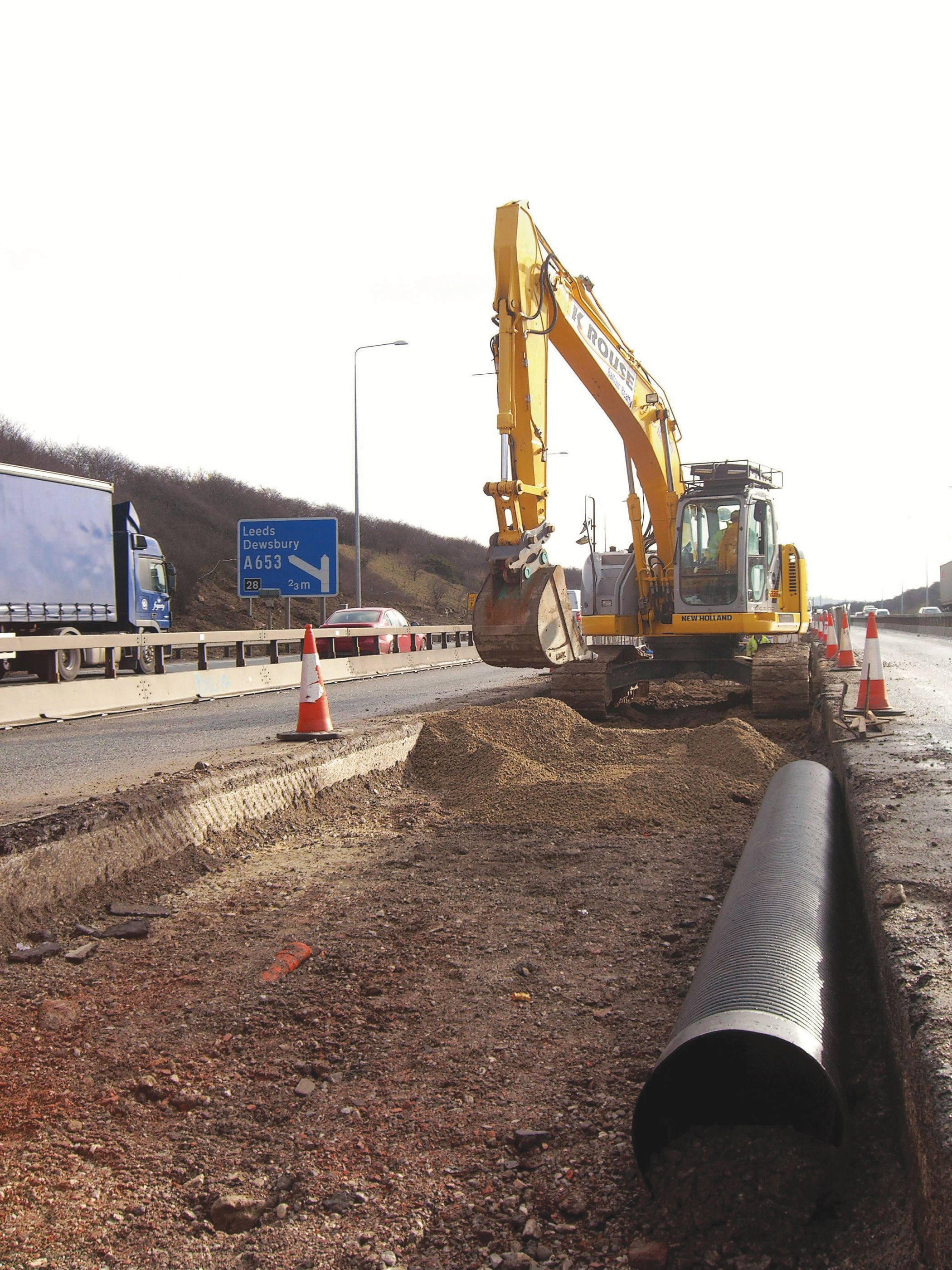 A New Holland E235B reduced tailswing tracked excavator at work on the motorway 