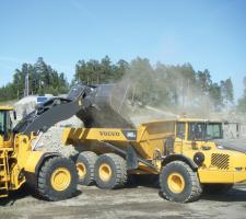 Excavator  unloading onto Volvo dump truck 