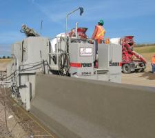 Concrete slipformer installing a barrier